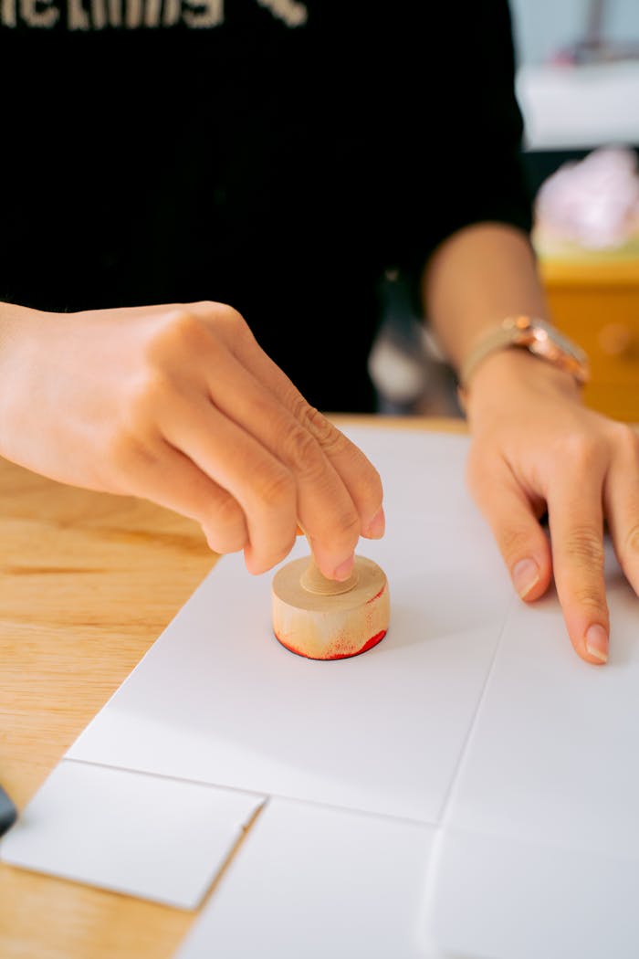 journey Close-up of a person using a wooden stamp on white paper indoors.
