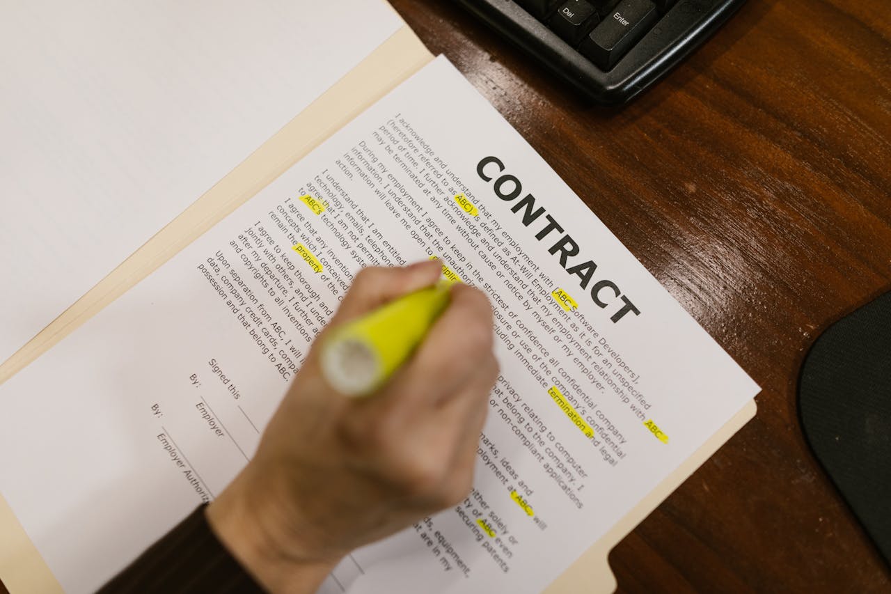 services-03 Focused view of a person highlighting text in a contract document on a wooden office desk.